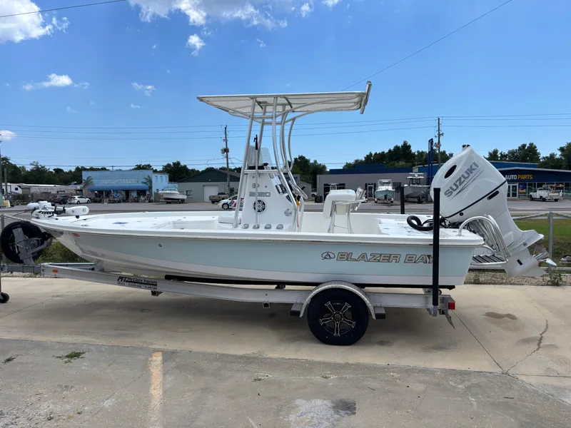 Slide: The Image of 2023 Blazer Bay 2020 boat on trailer, featuring Suzuki outboard motor, parked outdoors. - 23