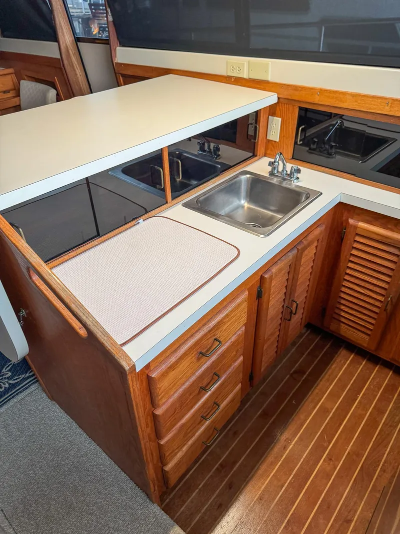 Slide: The Image of 1987 Mainship 40 Aft Cabin galley with sink, wooden cabinets, and countertop. - 15