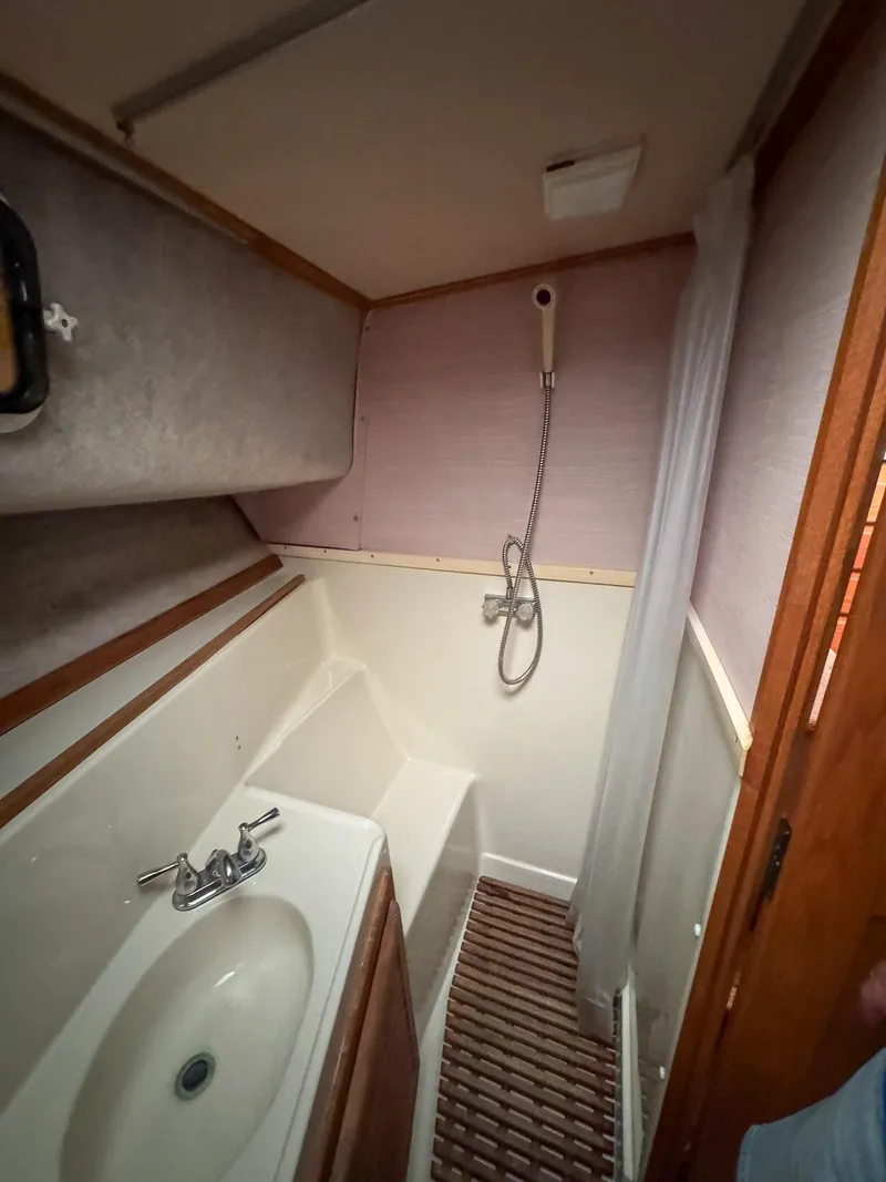 Slide: The Image of 1987 Mainship 40 Aft Cabin bathroom with sink, shower, and wooden accents. - 22