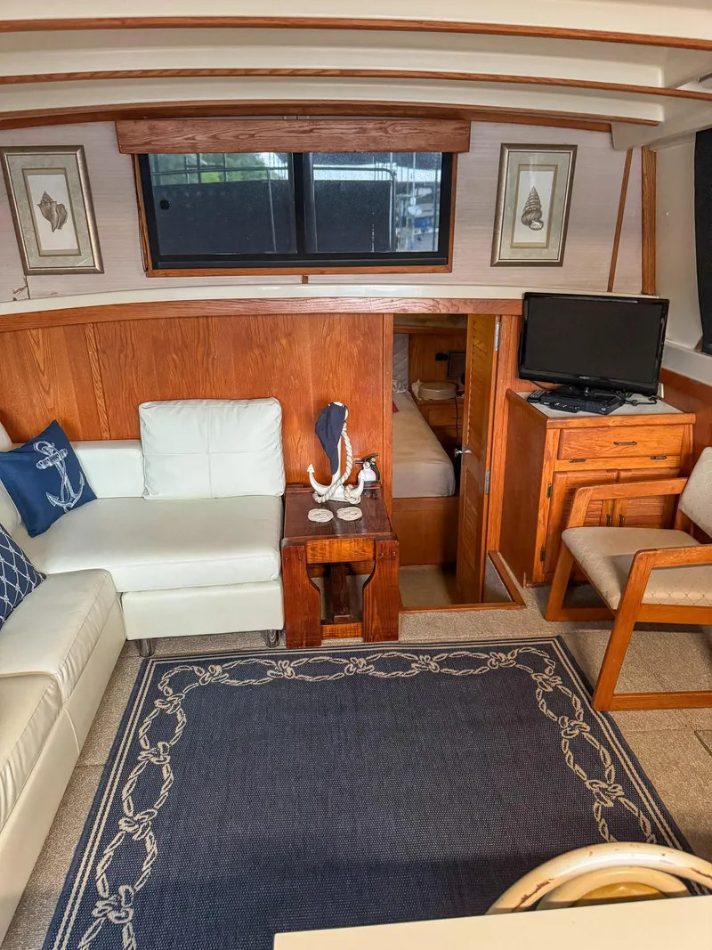 Slide: The Image of 1987 Mainship 40 Aft Cabin interior with cozy seating, nautical decor, and a small TV. - 27