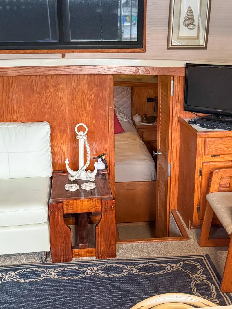 Slide: The Image of 1987 Mainship 40 Aft Cabin interior with cozy seating, wooden decor, and a small bedroom. - 31