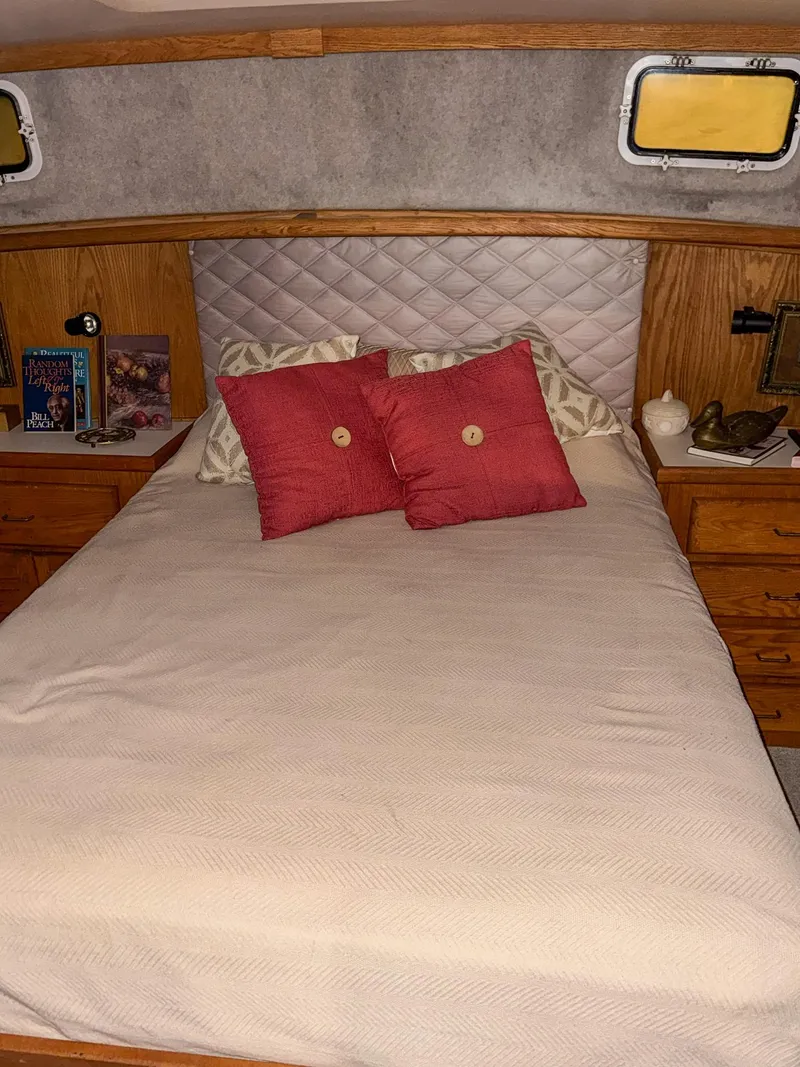 Slide: The Image of 1987 Mainship 40 Aft Cabin bedroom with cozy bed, red pillows, and wooden cabinetry. - 34