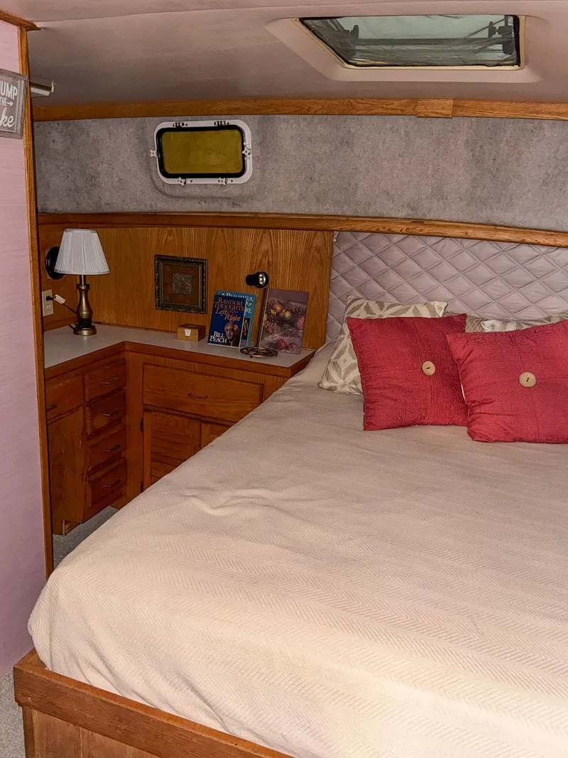 Slide: The Image of 1987 Mainship 40 Aft Cabin bedroom with cozy bed, wooden cabinetry, and decorative pillows. - 35