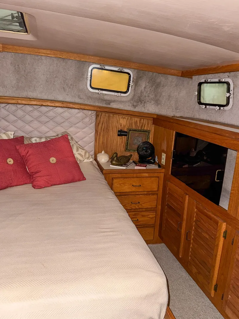 Slide: The Image of 1987 Mainship 40 Aft Cabin bedroom with bed, wooden cabinets, and portholes. - 36