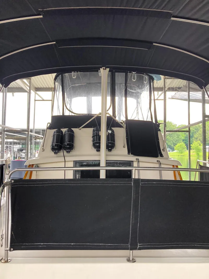 Slide: The Image of 1987 Mainship 40 Aft Cabin boat with black canopy in marina. - 7