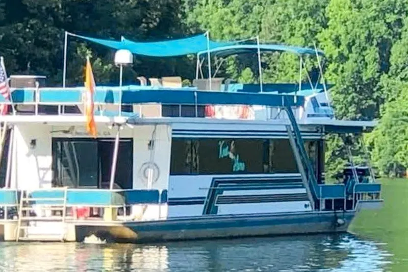 Slide: The Image of 1991 Sumerset 65 x 14 Widebody Houseboat on a serene lake with lush greenery. - 1