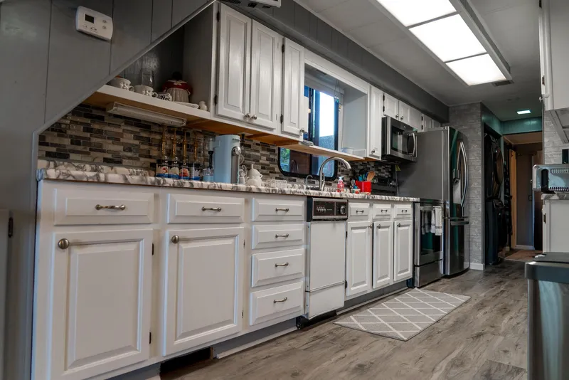 Slide: The Image of Modern kitchen interior of 1991 Sumerset 65 x 14 Widebody Houseboat, featuring white cabinetry and stainless appliances. - 12