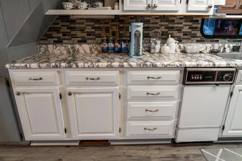 Slide: The Image of White kitchen cabinets and marble countertop in a 1991 Sumerset 65 x 14 Widebody Houseboat. - 15