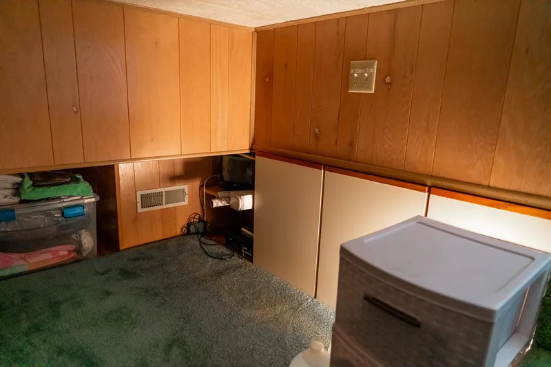 Slide: The Image of 1991 Sumerset 65 x 14 Widebody Houseboat interior with wood paneling and storage cabinets. - 24