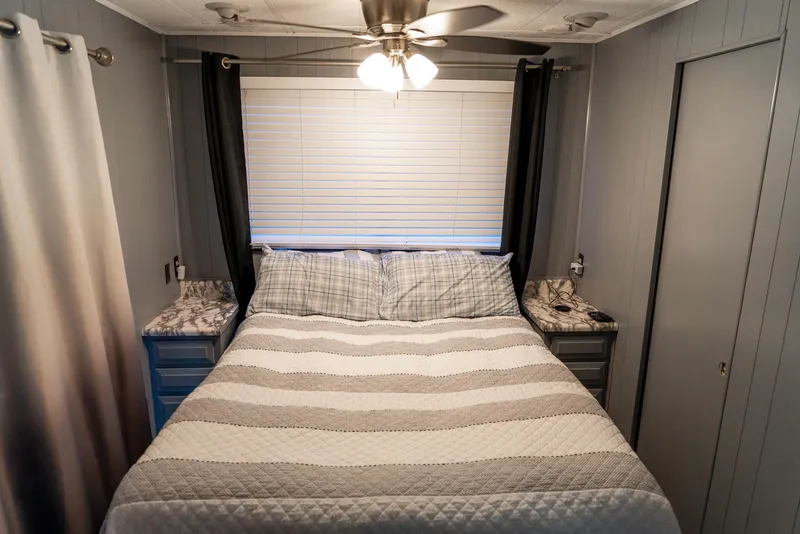 Slide: The Image of Cozy bedroom in 1991 Sumerset 65 x 14 Widebody Houseboat with striped bedding and ceiling fan. - 26