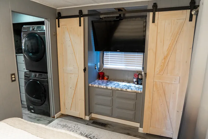 Slide: The Image of 1991 Sumerset 65 x 14 Widebody Houseboat interior with barn doors, TV, and laundry area. - 28