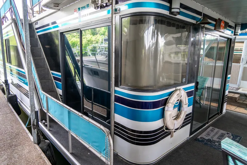 Slide: The Image of 1991 Sumerset 65 x 14 Widebody Houseboat with blue and white exterior, docked. - 36