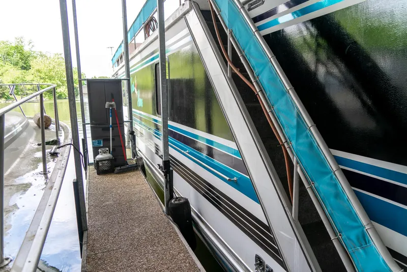 Slide: The Image of 1991 Sumerset 65 x 14 Widebody Houseboat docked, featuring blue and white exterior design. - 37