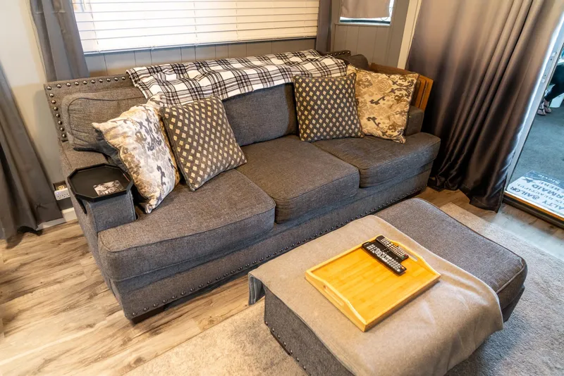 Slide: The Image of Cozy living area in a 1991 Sumerset 65 x 14 Widebody Houseboat with a gray sofa and cushions. - 4