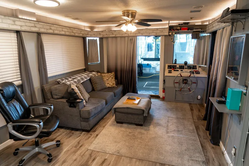 Slide: The Image of Interior of a 1991 Sumerset 65 x 14 Widebody Houseboat, featuring cozy seating and helm. - 5