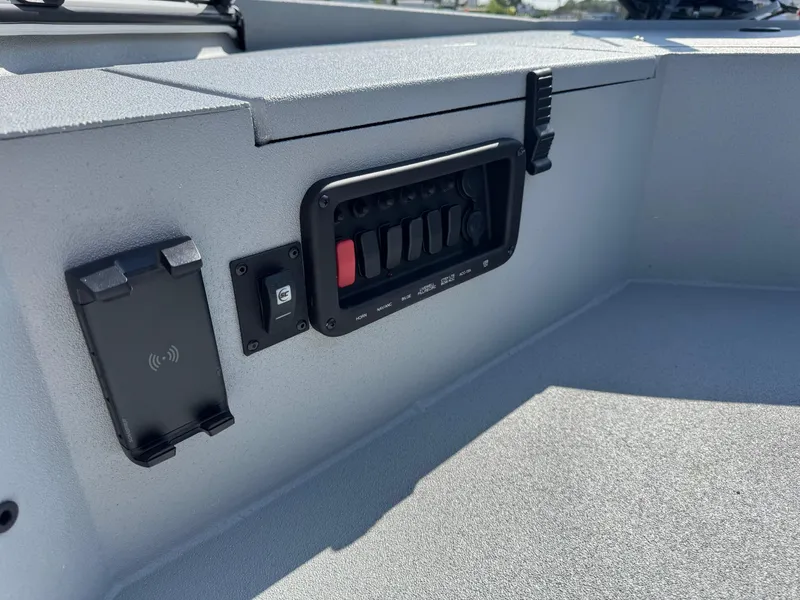 Slide: The Image of Control panel on 2025 Avid 18 Commander boat, featuring switches and a wireless charging pad. - 9