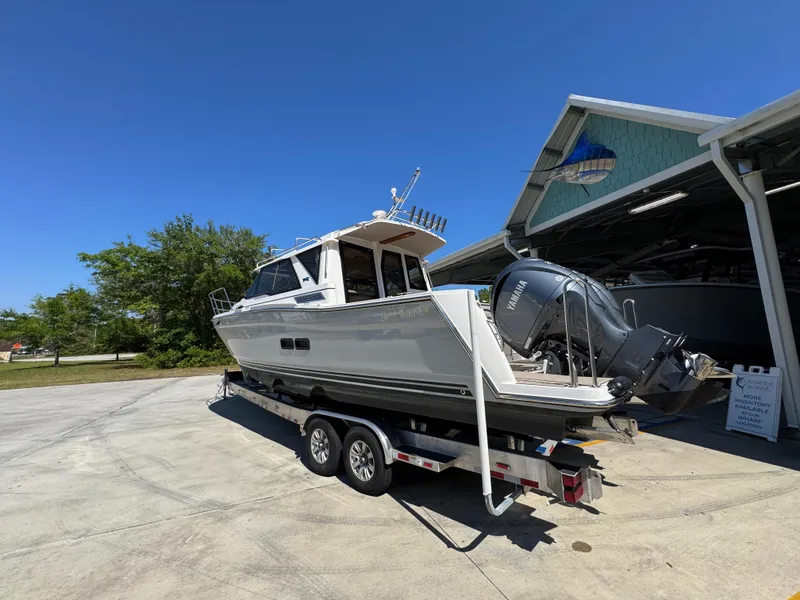 Slide: The Image of 2024 Cutwater C-288 Coupe boat on trailer, parked outdoors under clear blue sky. - 21