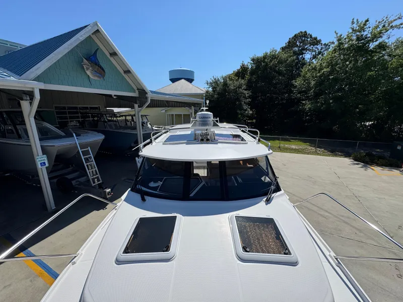 Slide: The Image of 2024 Cutwater C-288 Coupe boat docked near a marina building under clear blue skies. - 26