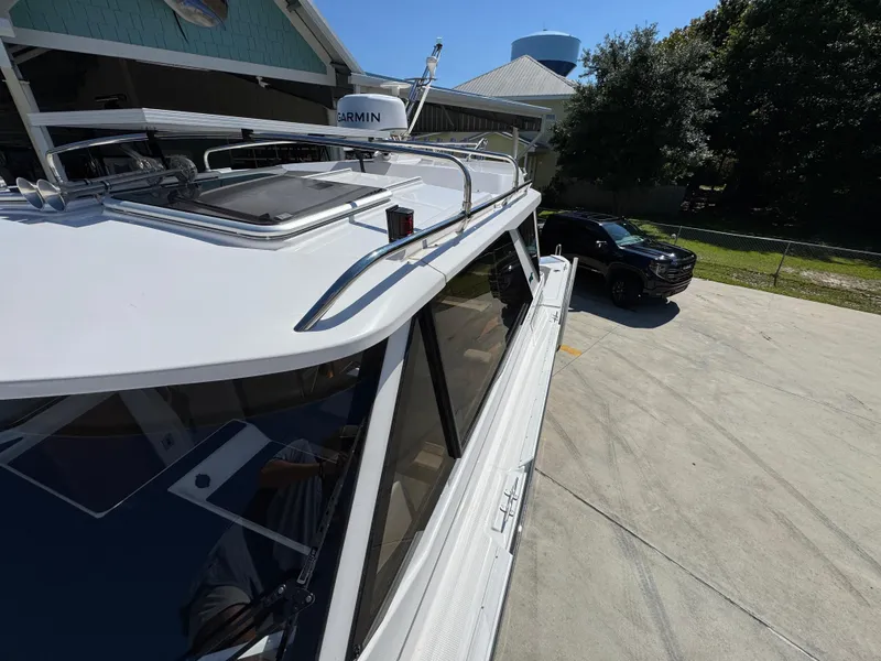 Slide: The Image of 2024 Cutwater C-288 Coupe boat parked near a black vehicle in a sunny driveway. - 29