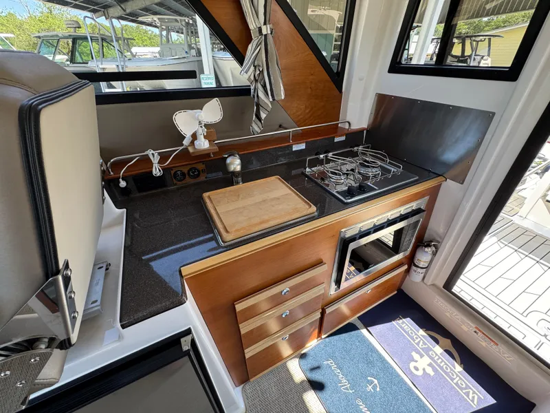 Slide: The Image of 2024 Cutwater C-288 Coupe interior kitchen with stove, cutting board, and storage drawers. - 40