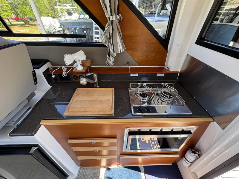 Slide: The Image of 2024 Cutwater C-288 Coupe kitchen with stove, sink, and wooden cabinetry. - 41