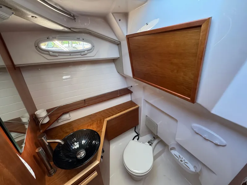 Slide: The Image of 2024 Cutwater C-288 Coupe bathroom with modern sink, toilet, and wooden cabinetry. - 49
