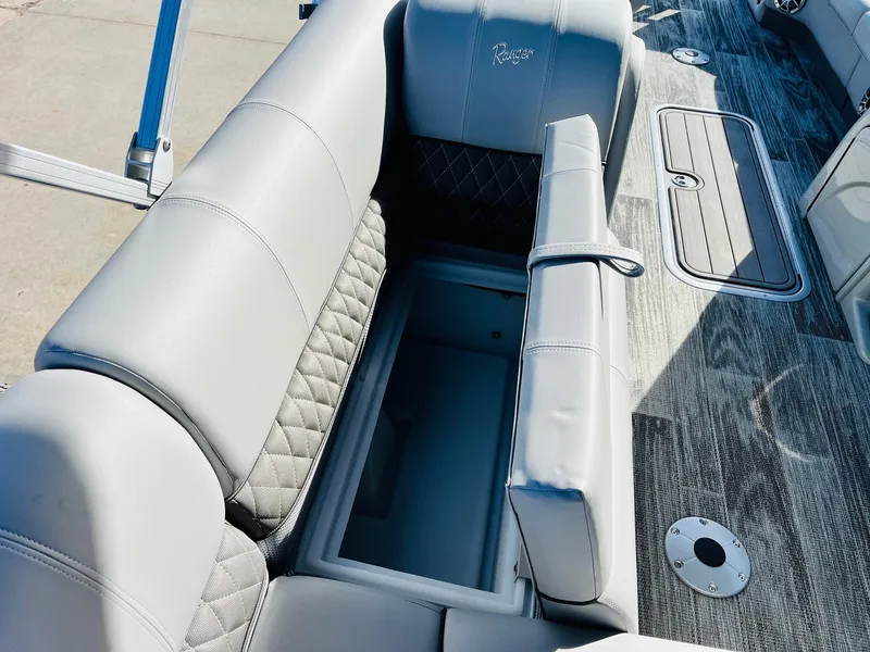 Slide: The Image of 2025 Ranger Reata 223FC boat interior with open storage compartment and gray seating. - 29