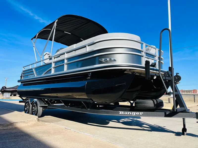 Slide: The Image of 2025 Ranger Reata 223FC pontoon boat on trailer, sleek design, black and silver finish. - 3