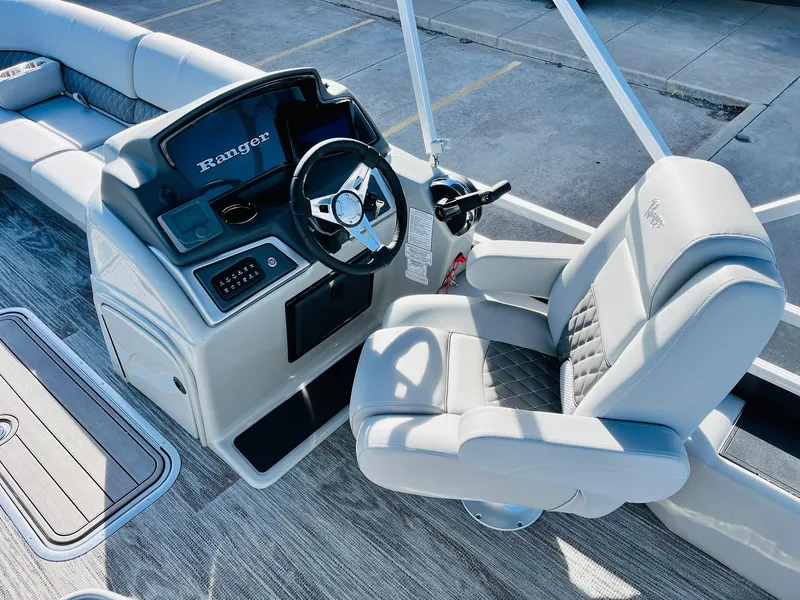Slide: The Image of 2025 Ranger Reata 223FC boat interior with steering wheel and plush seating. - 31