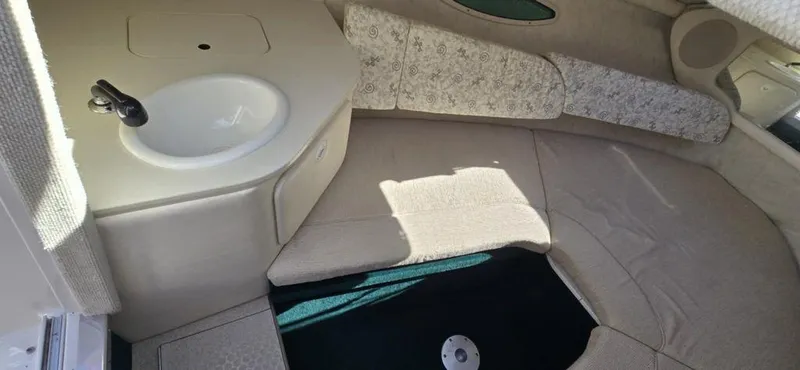 Slide: The Image of 2002 Sea Ray 225 Weekender cabin interior with sink and seating area. - 5