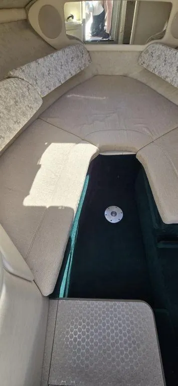 Slide: The Image of 2002 Sea Ray 225 Weekender cabin interior with beige seating and storage space. - 6