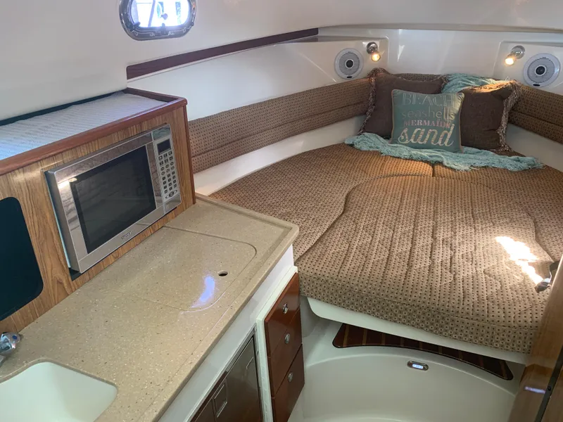 Slide: The Image of 2008 Pursuit 315 OS cabin interior with bed, microwave, and sink. - 15