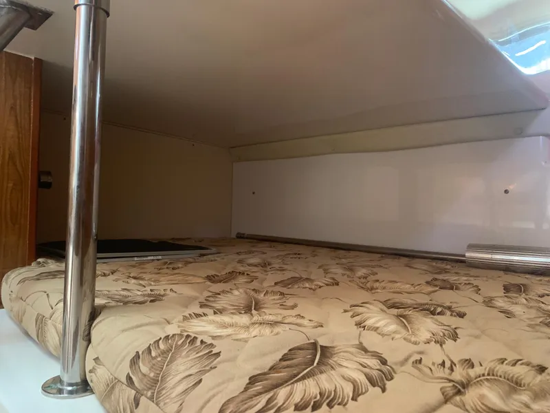 Slide: The Image of 2008 Pursuit 315 OS cabin interior with floral-patterned bedding and metal support poles. - 16