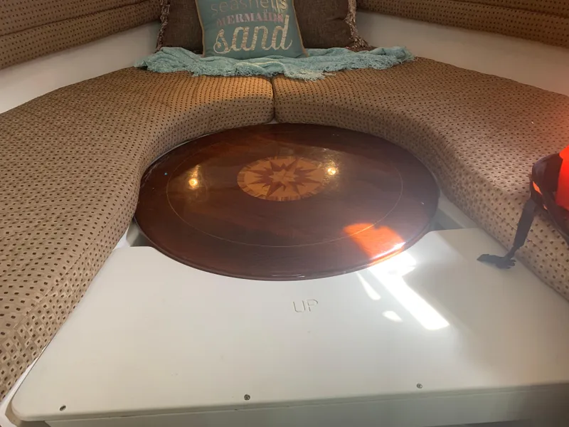 Slide: The Image of 2008 Pursuit 315 OS cabin interior with circular wooden table and cushioned seating. - 17