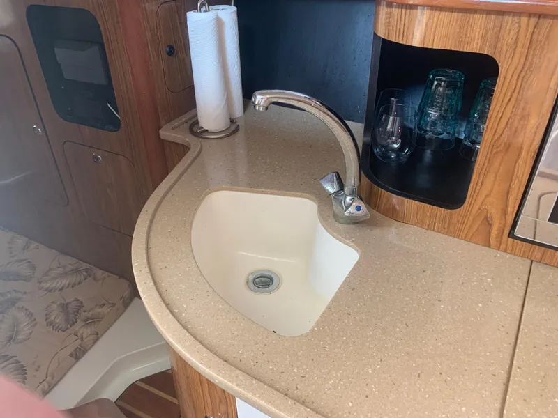 Slide: The Image of 2008 Pursuit 315 OS boat interior with sink, faucet, and wooden cabinetry. - 21