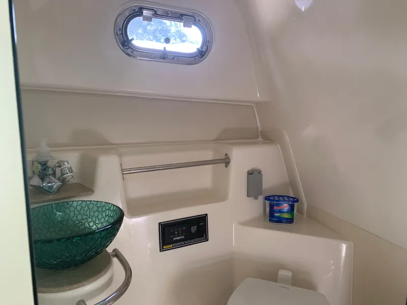Slide: The Image of 2008 Pursuit 315 OS boat bathroom with glass sink and porthole window. - 23