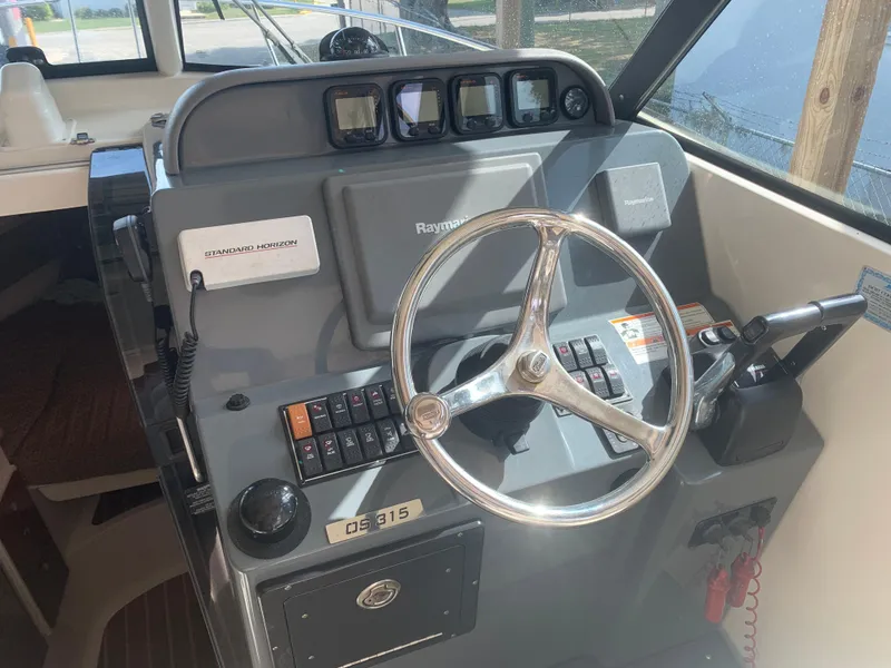 Slide: The Image of 2008 Pursuit 315 OS boat dashboard with steering wheel and control panel. - 7