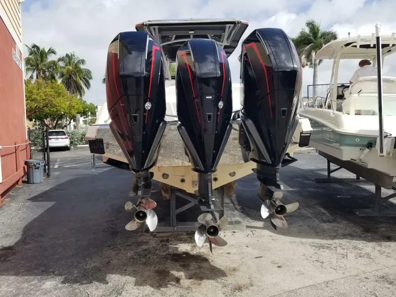 Slide: The Image of 2020 Nor-Tech Center Console boat with triple outboard engines, docked outdoors. - 6