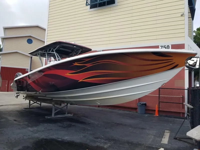 Slide: The Image of 2020 Nor-Tech Center Console boat with vibrant flame design, docked outdoors. - 7