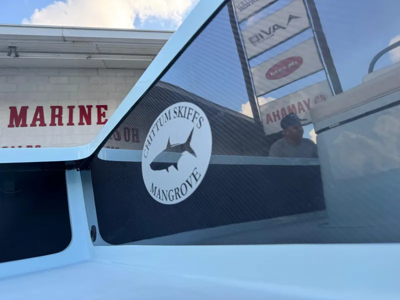 Slide: The Image of 2024 Chittum Skiffs 21 Mangrove boat with logo, displayed at a marine dealership. - 4