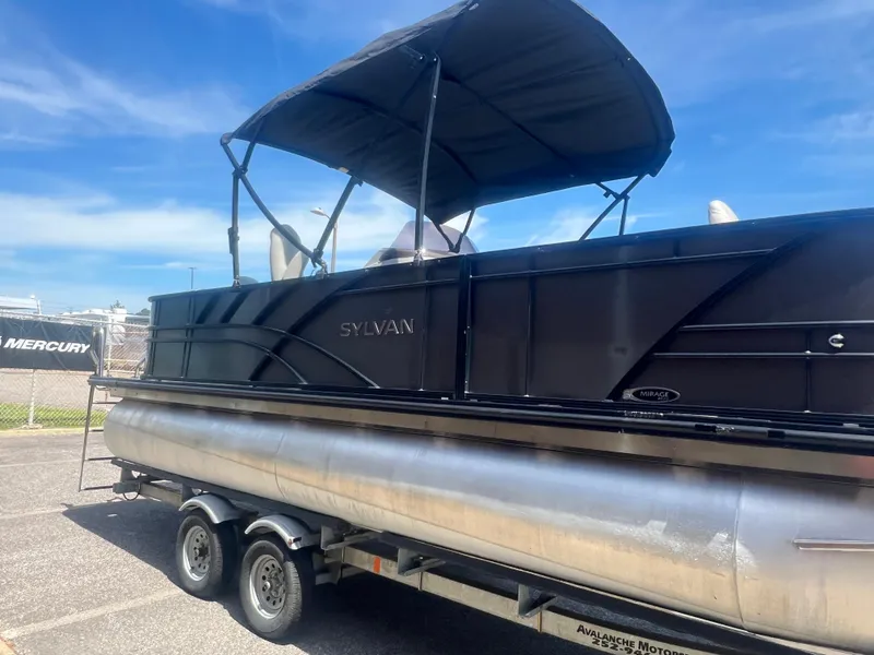 Slide: The Image of 2021 Sylvan Mirage Fish 8522 Party Fish pontoon boat on trailer, under blue sky. - 12