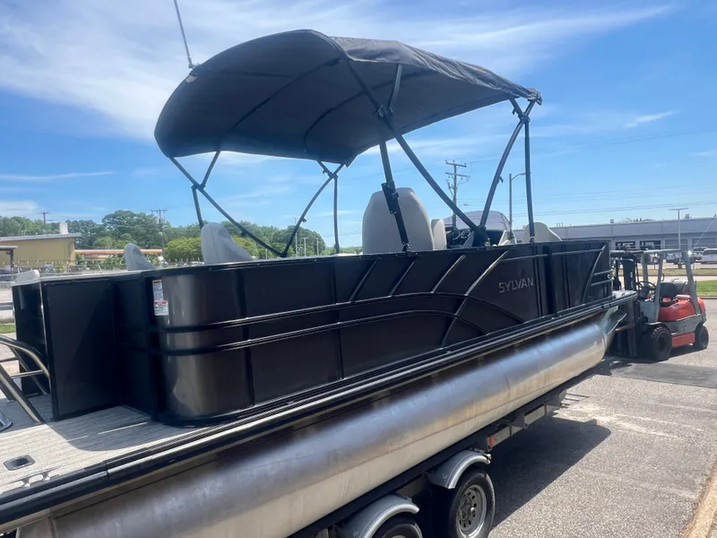 Slide: The Image of 2021 Sylvan Mirage Fish 8522 Party Fish pontoon boat on trailer, under sunny sky. - 13