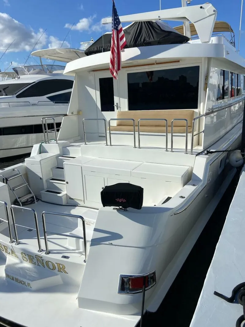 Slide: The Image of 1989 Hatteras Custom Cockpit yacht docked, featuring spacious deck and American flag. - 11
