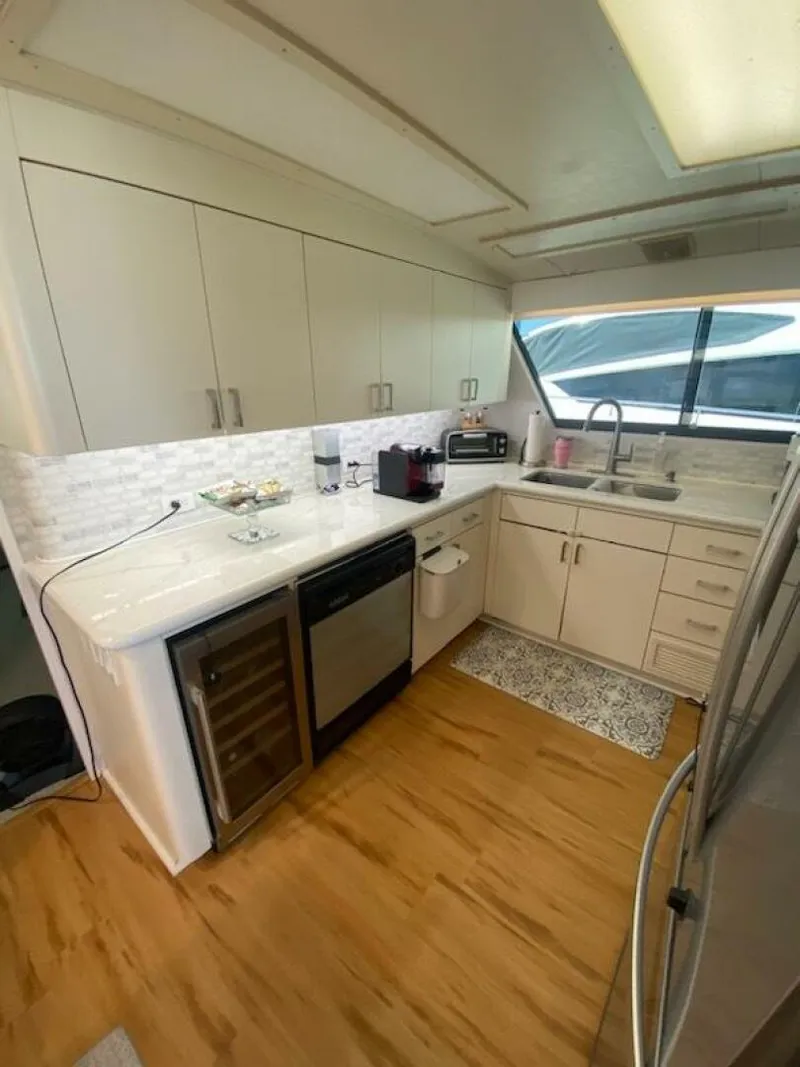 Slide: The Image of 1989 Hatteras Custom Cockpit kitchen with modern appliances, white cabinetry, and wood flooring. - 21