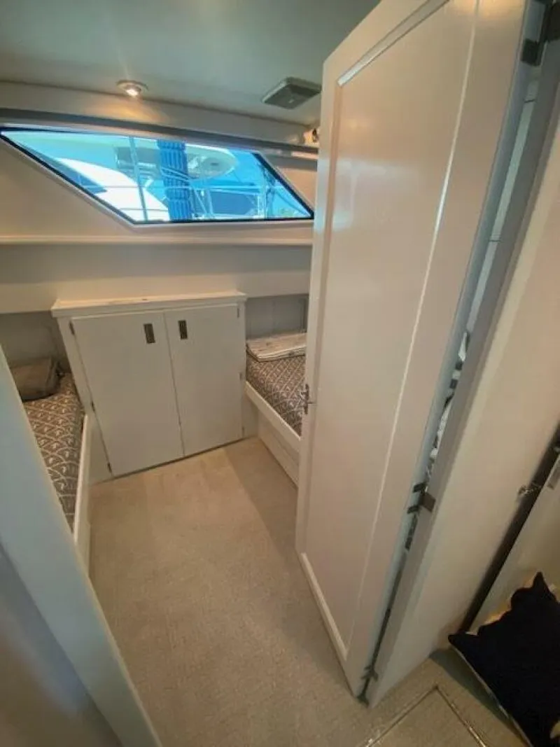 Slide: The Image of 1989 Hatteras Custom Cockpit interior with twin beds and storage, featuring a sleek window design. - 27