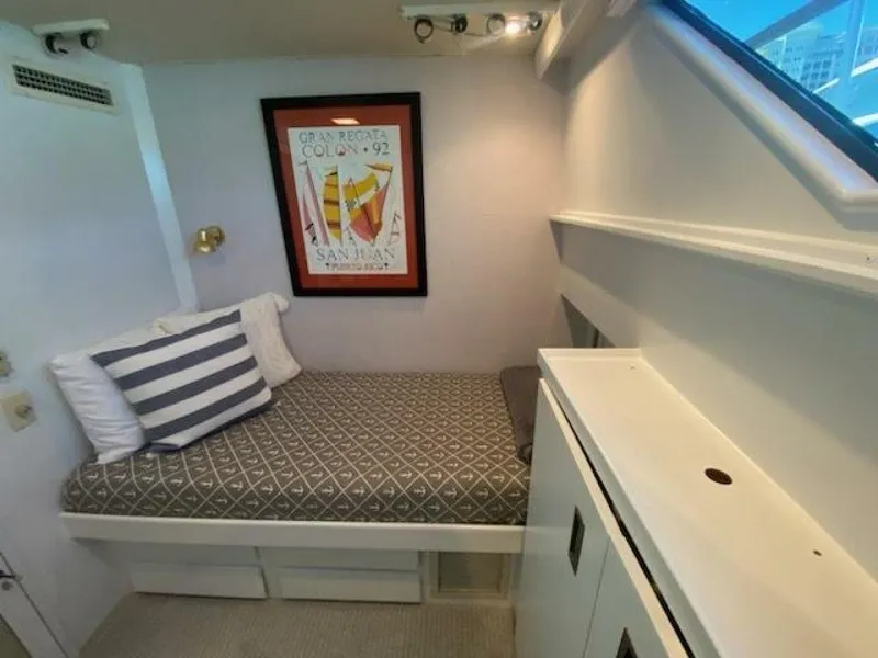 Slide: The Image of 1989 Hatteras Custom Cockpit interior with cozy bed, nautical decor, and framed artwork. - 30