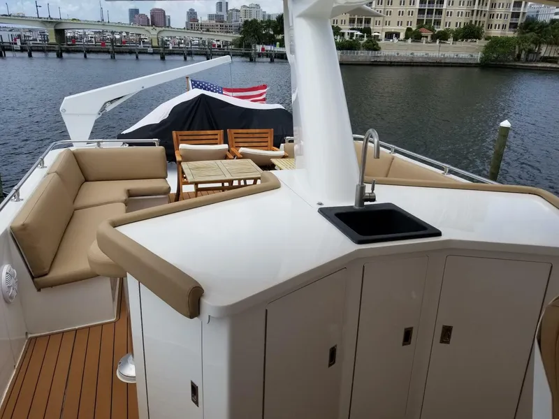 Slide: The Image of 1989 Hatteras Custom Cockpit yacht with outdoor seating, sink, and scenic waterfront view. - 6