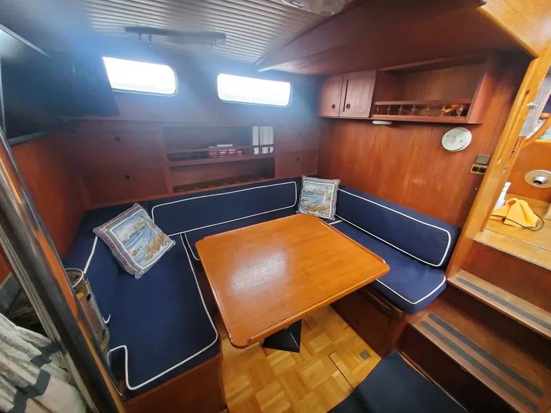Slide: The Image of Cozy interior of 1982 Nauticat 38 sailboat with wooden table and blue cushioned seating. - 3