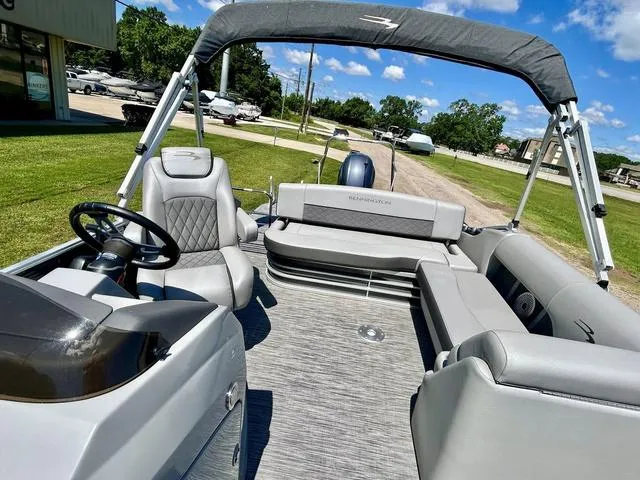 Slide: The Image of 2020 Bennington 22 SX pontoon boat with gray seating and canopy, parked on grass under blue sky. - 7