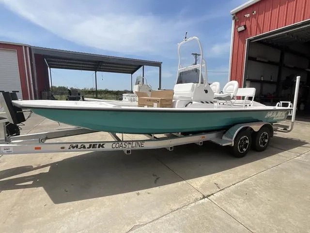 Slide: The Image of 2025 Majek 2206 Illusion boat on trailer, parked outside a red building. - 1